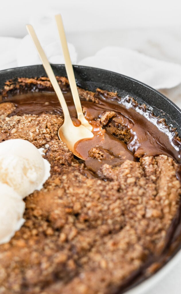 closeup of two gold spoons in a pool of gooey pumpkin caramel in pumpkin lava cake.