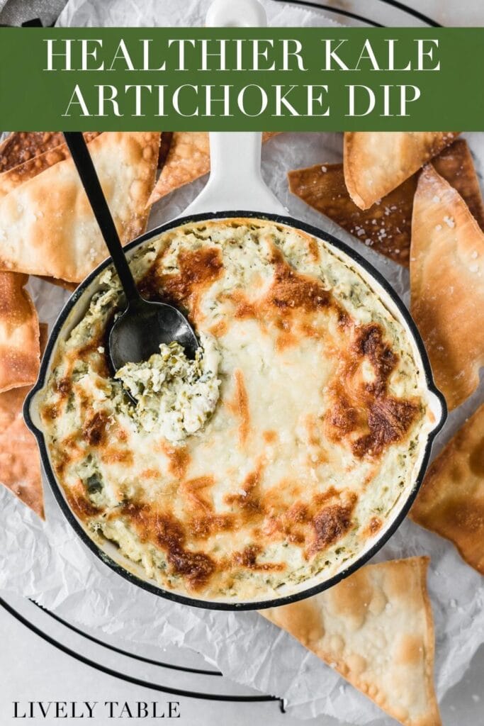 kale artichoke dip in a white skillet with a black spoon in it surrounded by wonton chips with text overlay.