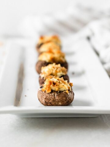 boursin stuffed mushrooms lined up on a white serving platter.