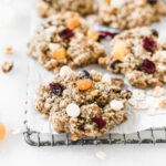 closeup of a fall harvest oatmeal cookie on a cooling rack with more cookies in the background.