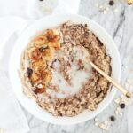 overhead view of caramelized banana chocolate oatmeal in a white bowl with a white napkin.