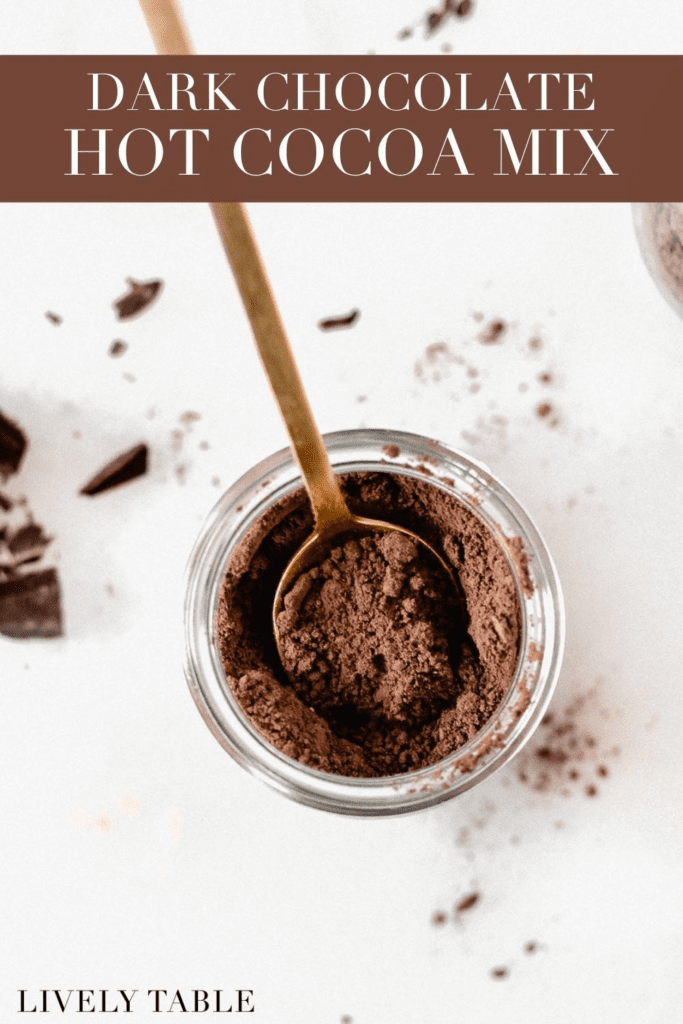 overhead view of dark chocolate hot cocoa mix in a jar with a gold spoon in it with text overlay.