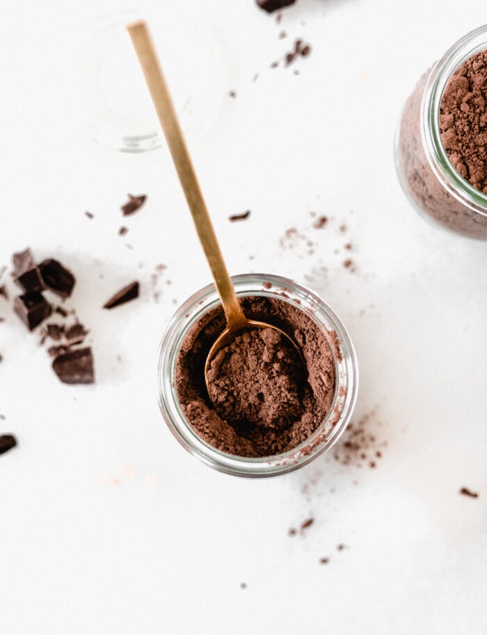 overhead view of homemade dark hot cocoa mix in a glass jar with a gold spoon in it.