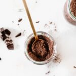 overhead view of dark chocolate hot cocoa mix in a jar with a gold spoon in it.