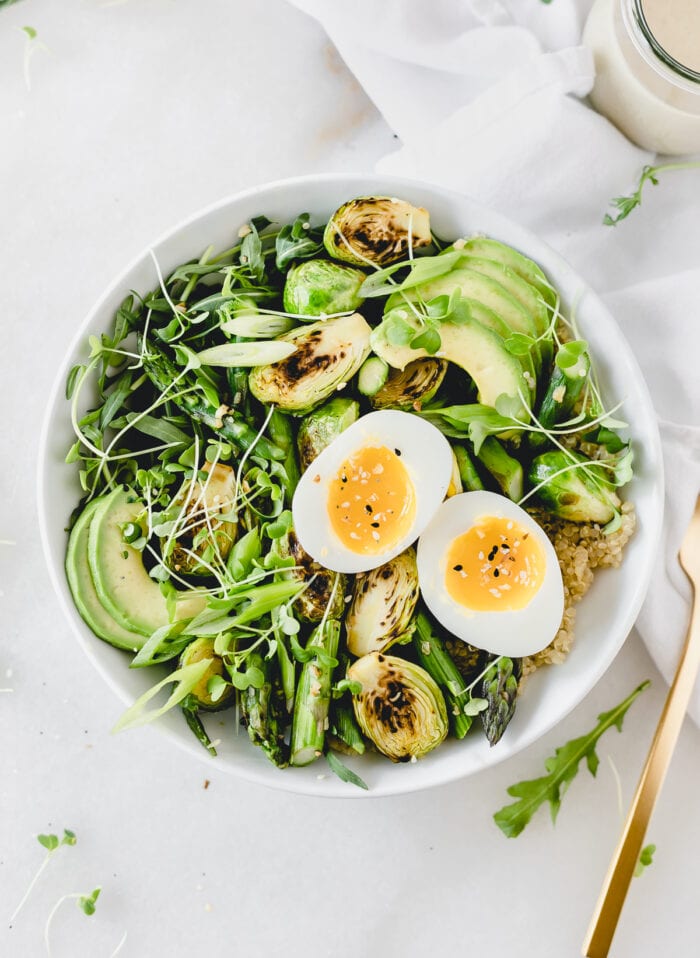 overhead view of spring green grain bowl with a soft boiled egg on top without dressing.