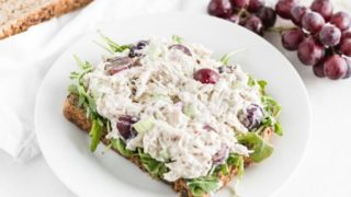 greek yogurt chicken salad with grapes on top of a piece of bread on a white plate.