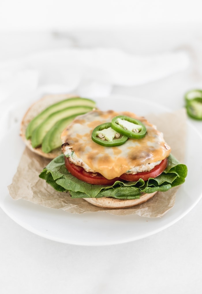 Healthy Jalapeno Chicken Burger with the top bun off, topped with cheese and jalapeno slices.