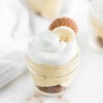 Closeup view of a glass jar of homemade banana pudding garnished with a vanilla wafer and a banana slice.