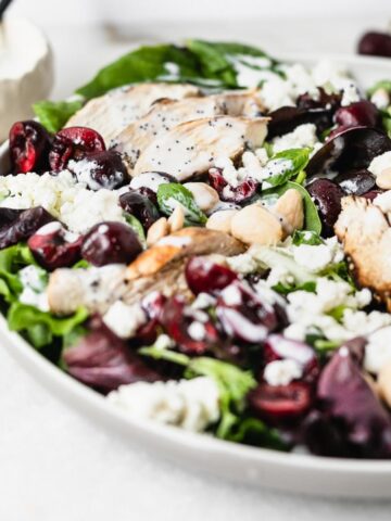 closeup of cherry almond grilled chicken salad drizzled with creamy poppy seed dressing.