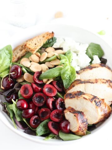 Closeup overhead view of cherry almond grilled chicken salad in a white bowl.