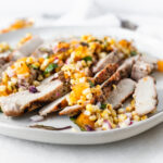 sliced pork chops topped with grilled apricot and corn salsa on a plate.