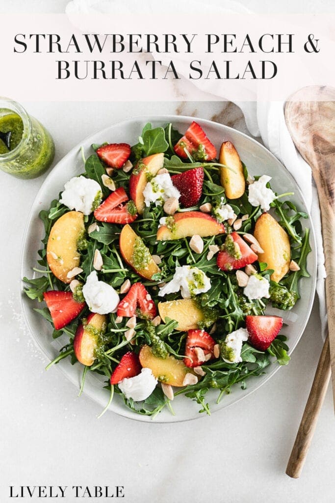 overhead view of strawberry peach & burrata arugula salad on a white plate with text overlay.