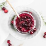 overhead view of spoon lifting cranberry sauce from a jar.