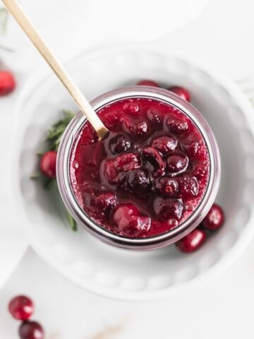 overhead view of spoon lifting cranberry sauce from a jar.
