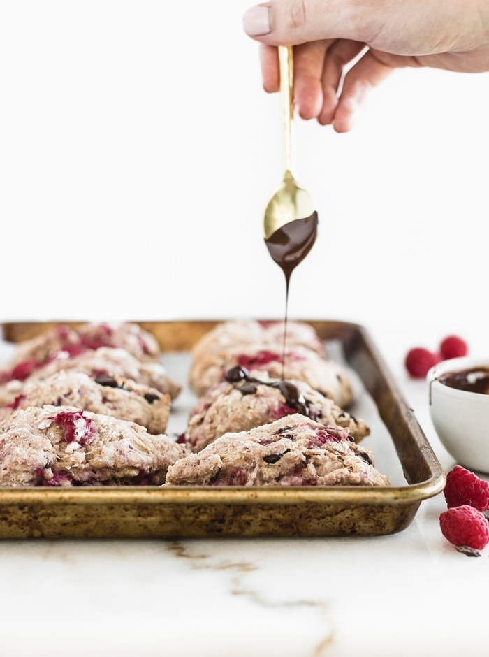 raspberry scones getting drizzled by dark chocolate