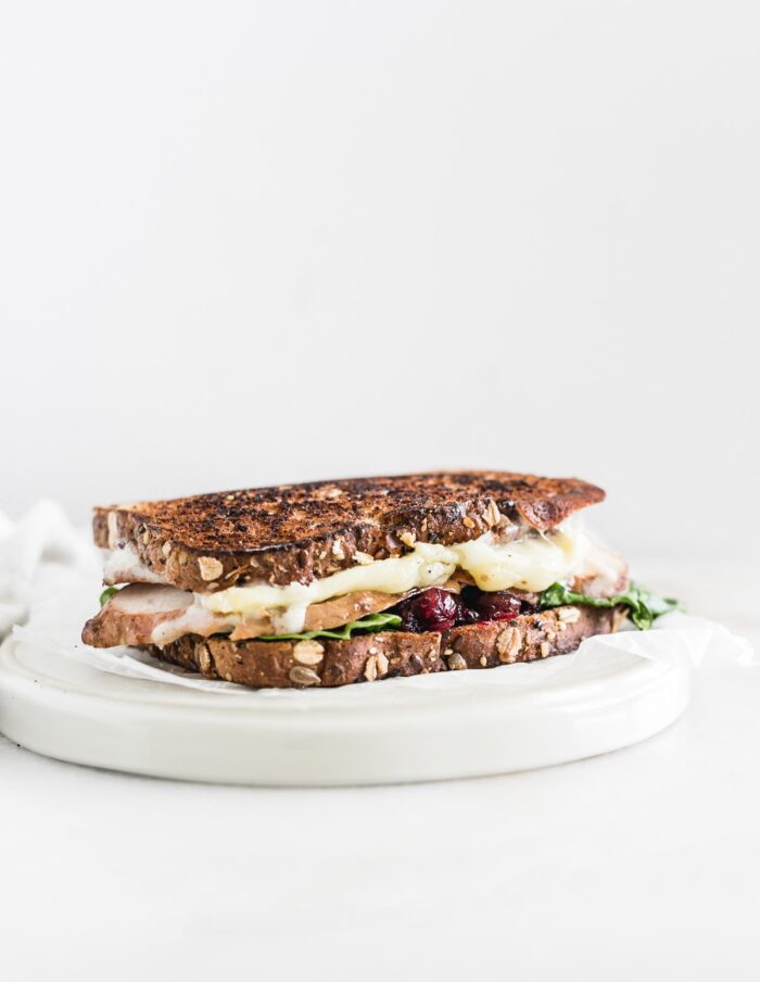 cranberry brie turkey sandwich on a white plate.