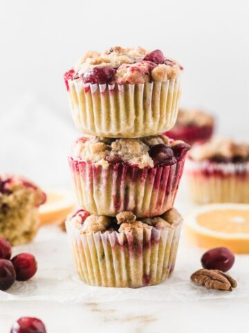 3 cranberry orange streusel muffins stacked on top of each other.