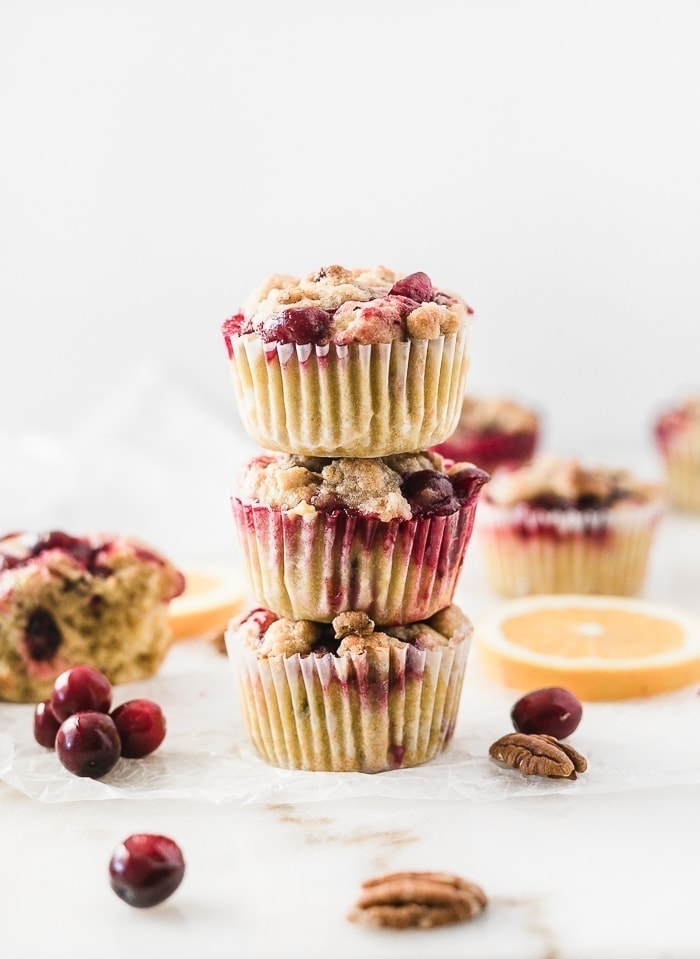 three cranberry orange crumb muffins stacked on top of each other.