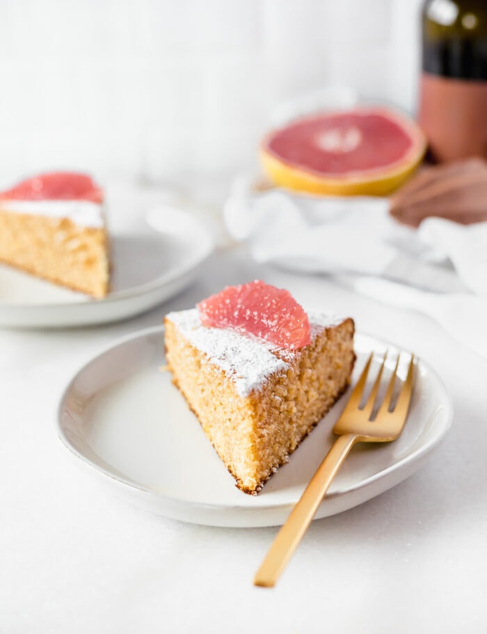 slice of grapefruit olive oil cake with a gold fork on a plate.