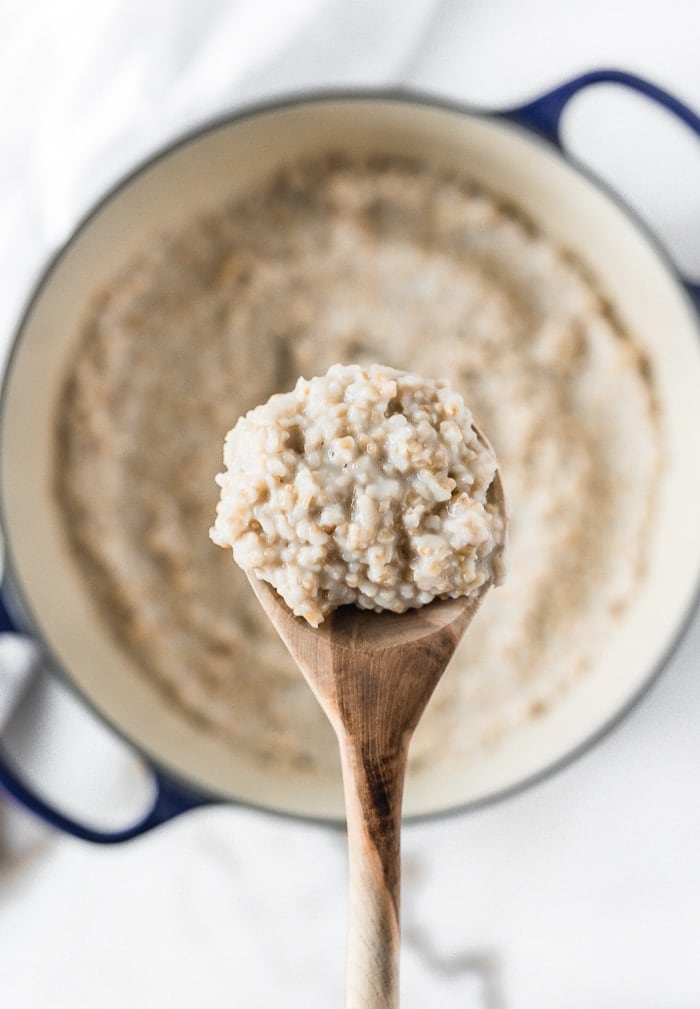 overhead shot of a spoon lifting steel cut oatmeal from a dutch oven.