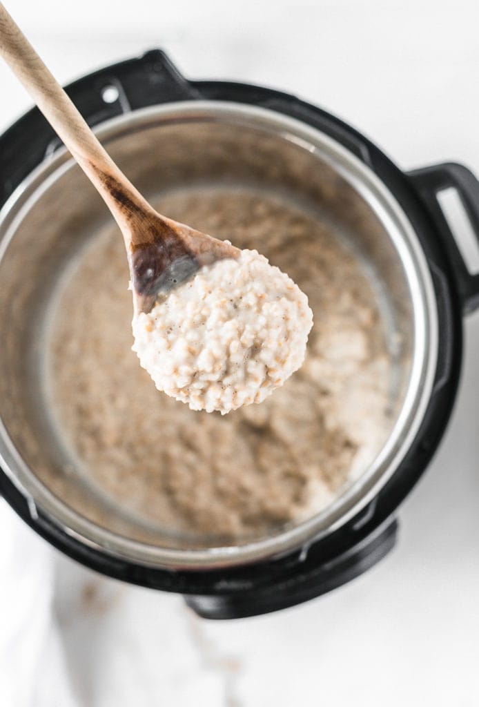 overhead shot of a wooden spoon lifting steel cut oatmeal from an Instant Pot.