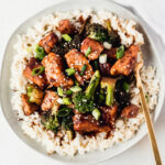 overhead view of sticky pomegranate ginger chicken with broccoli on top of coconut brown rice.