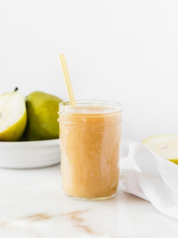 vanilla bean pear butter in a glass jar with a gold spoon in it.