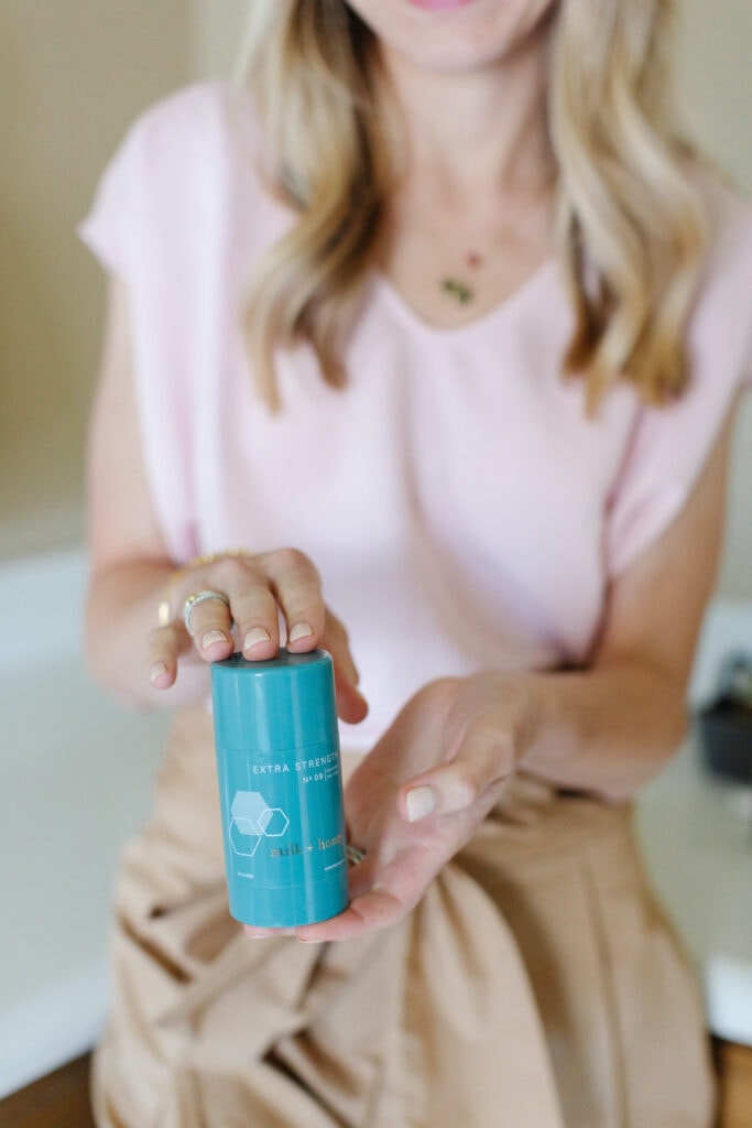 woman holding a blue bottle of deodorant.
