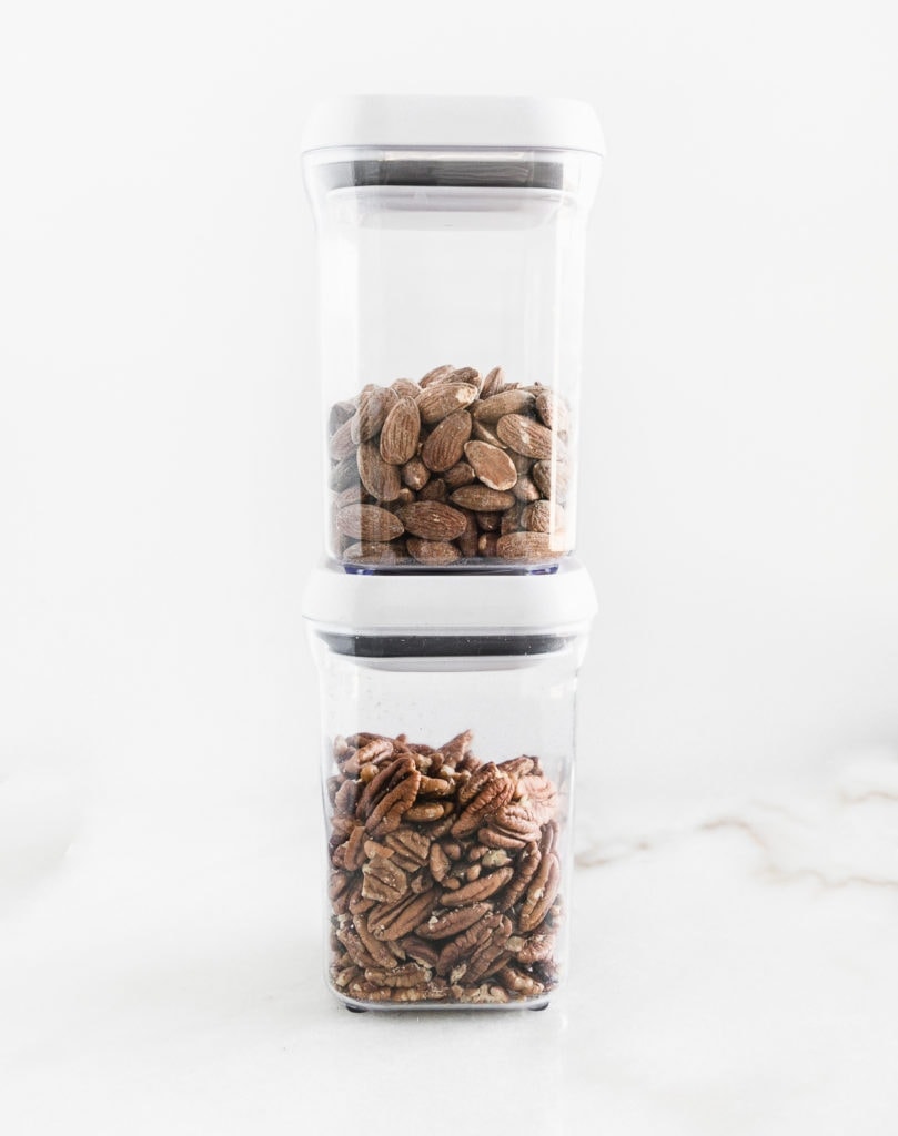 two clear plastic canisters with nuts in them stacked on top of each other.