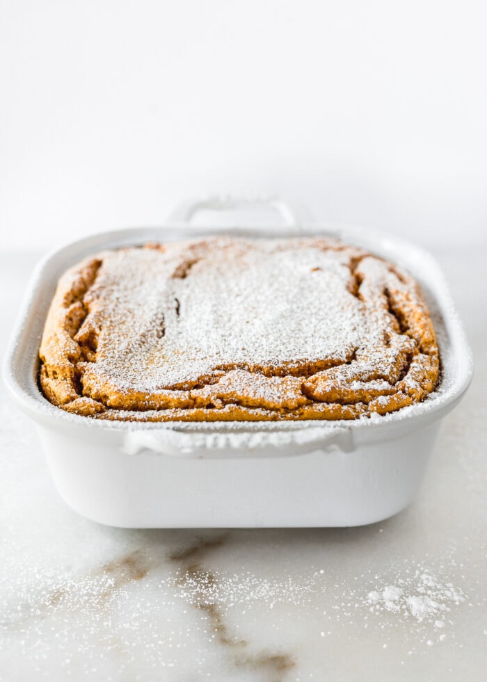 cinnamon ginger carrot souffle topped with powdered sugar in a white square baking dish.