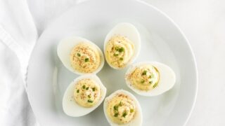 greek yogurt deviled eggs topped with chives on a white plate.