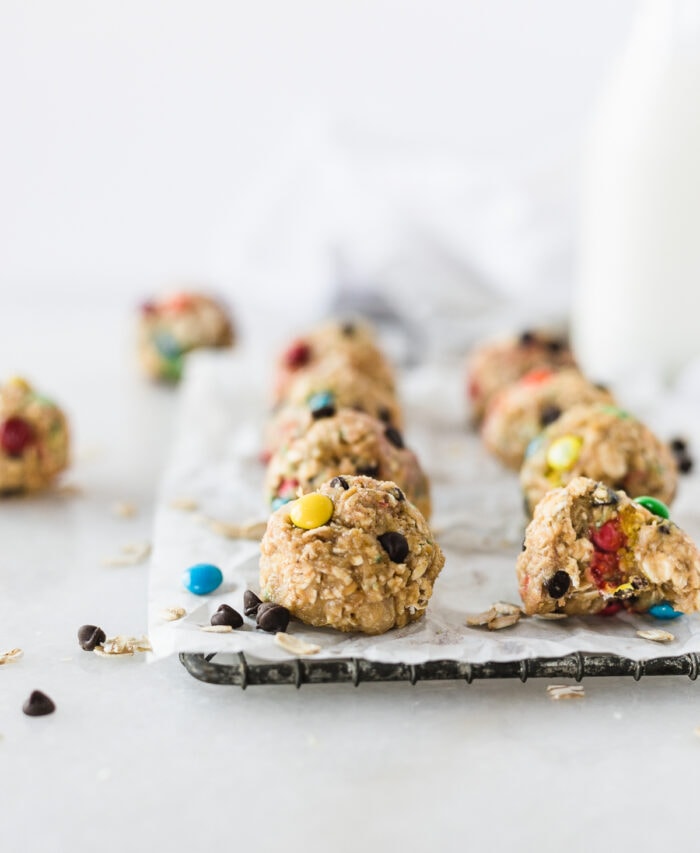 no bake monster cookie dough balls on a wire rack with a bite taken out of one.