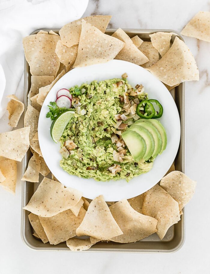 Caramelized onion guacamole on a plate with chips.