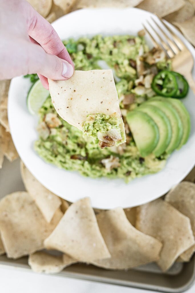 Close up of caramelized onion guacamole on a chip.