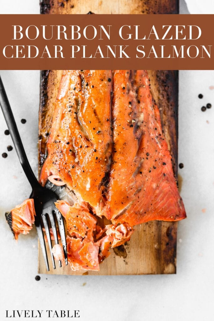 overhead view of a salmon filet on top of a cedar plank with a black fork cutting away a piece with text overlay.