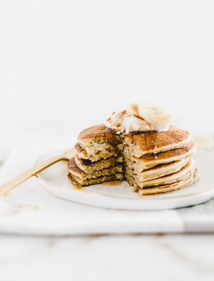 stack of banana chai pancakes on a white plate with a bite cut out.