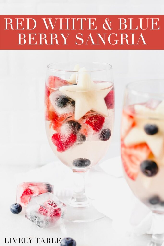 red white and blue sangria in a goblet with berry ice cubes and blueberries around it with text overlay..