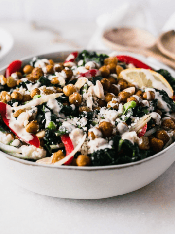 Moroccan chickpea kale salad drizzled with tahini dressing in a grey bowl.