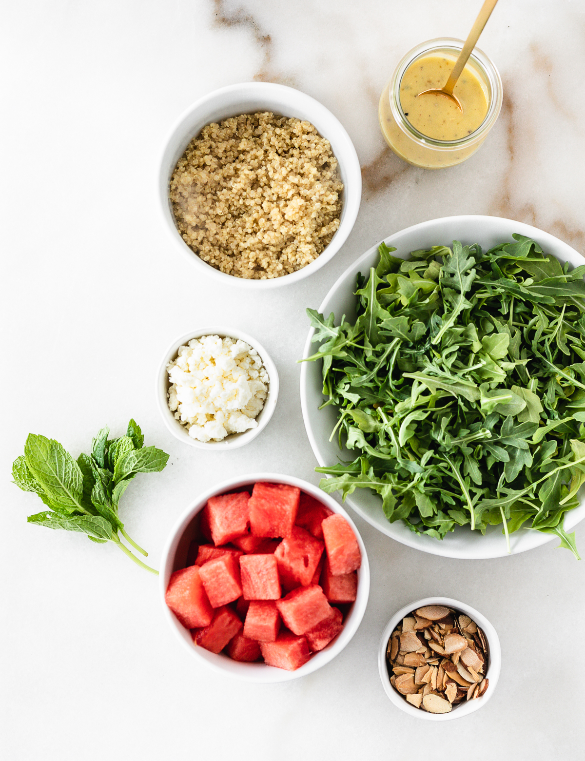 overhead view of ingredients needed to make watermelon arugula salad with feta and quinoa.