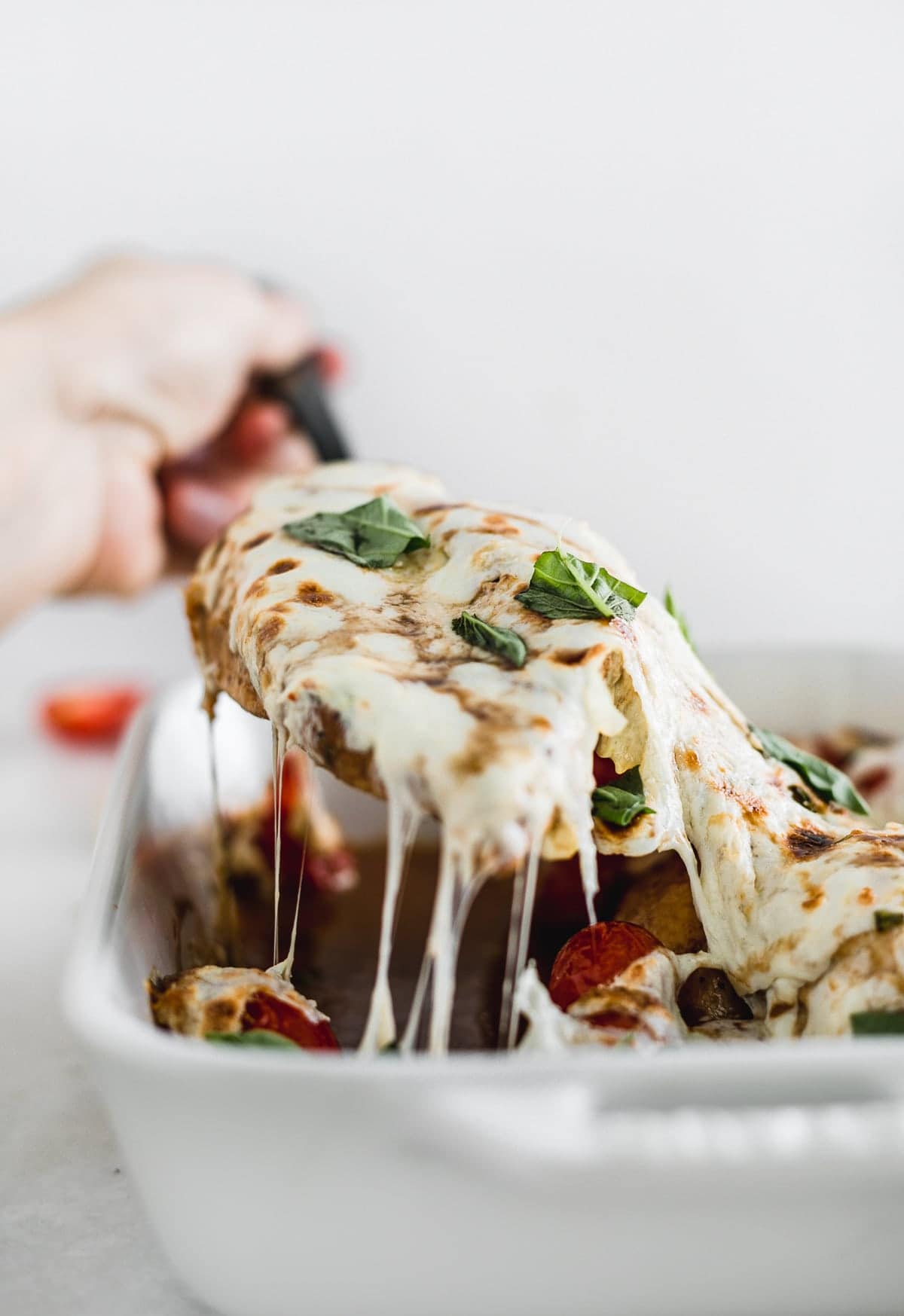 Grabbing a piece of easy oven baked Caprese chicken.