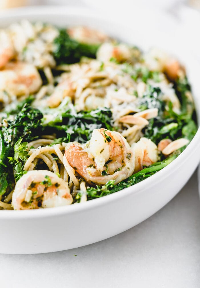 closeup of a shrimp in easy pesto pasta with shrimp and broccoli in a white bowl.