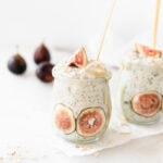 maple tahini fig overnight oats in a glass jar with a gold spoon in it with fresh figs in the background,