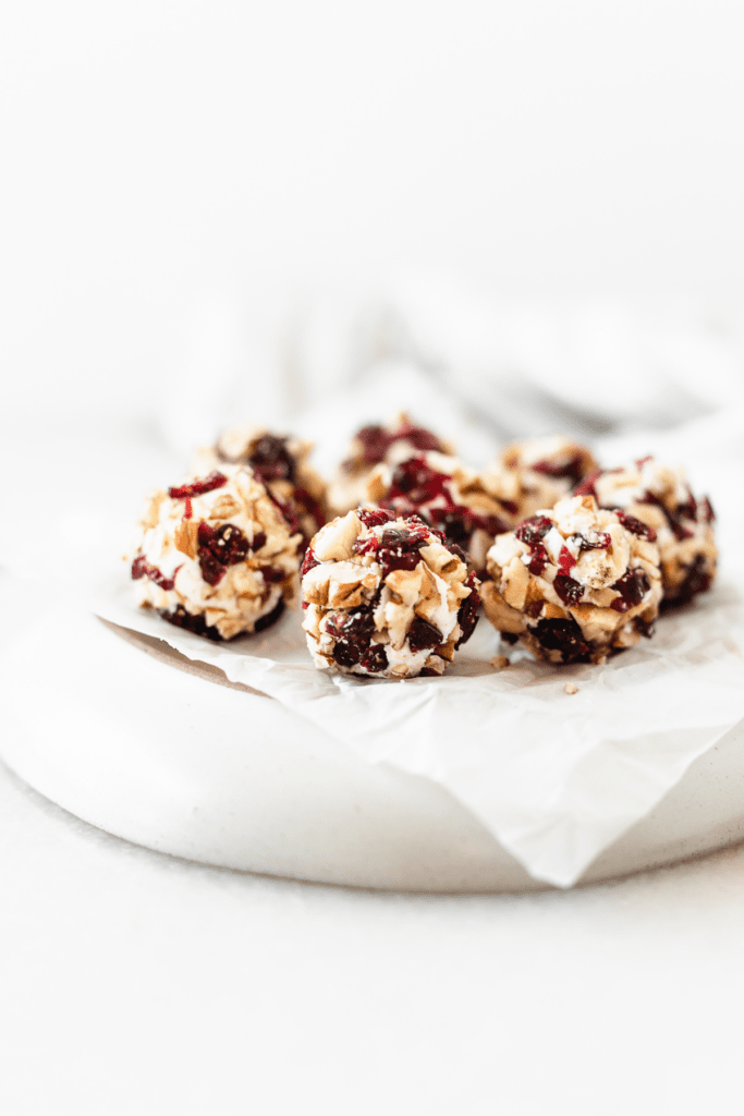 cranberry pecan mini goat cheese balls on a grey plate lined with parchment.