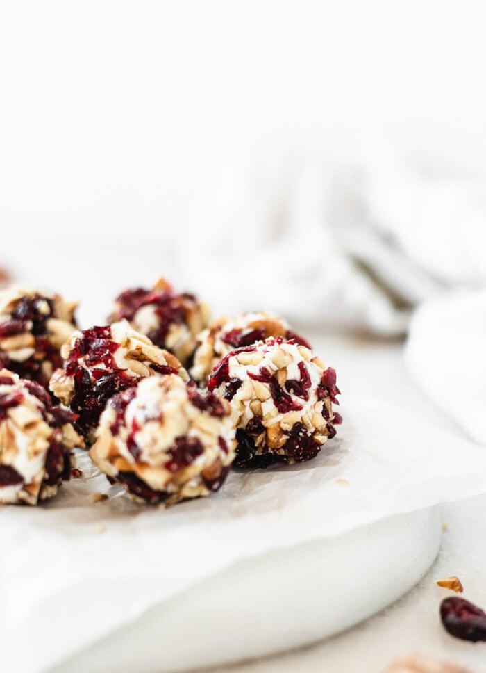 closeup of mini cranberry pecan goat cheese balls on a grey plate.