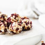 Close up of cranberry pecan mini goat cheese balls on a grey plate lined with parchment.