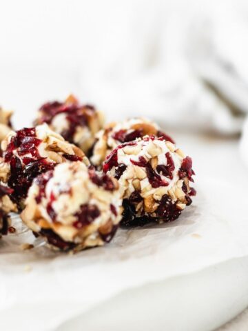 Close up of cranberry pecan mini goat cheese balls on a grey plate lined with parchment.