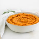 brown butter sage mashed sweet potatoes in a grey bowl with melted butter on top.