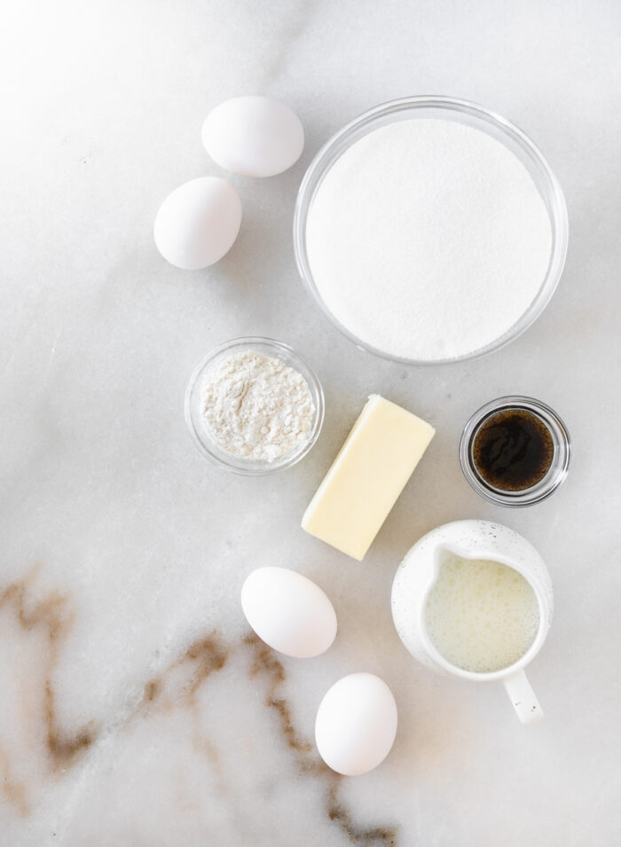 overhead view of ingredients needed to make buttermilk pie on a white marble background.