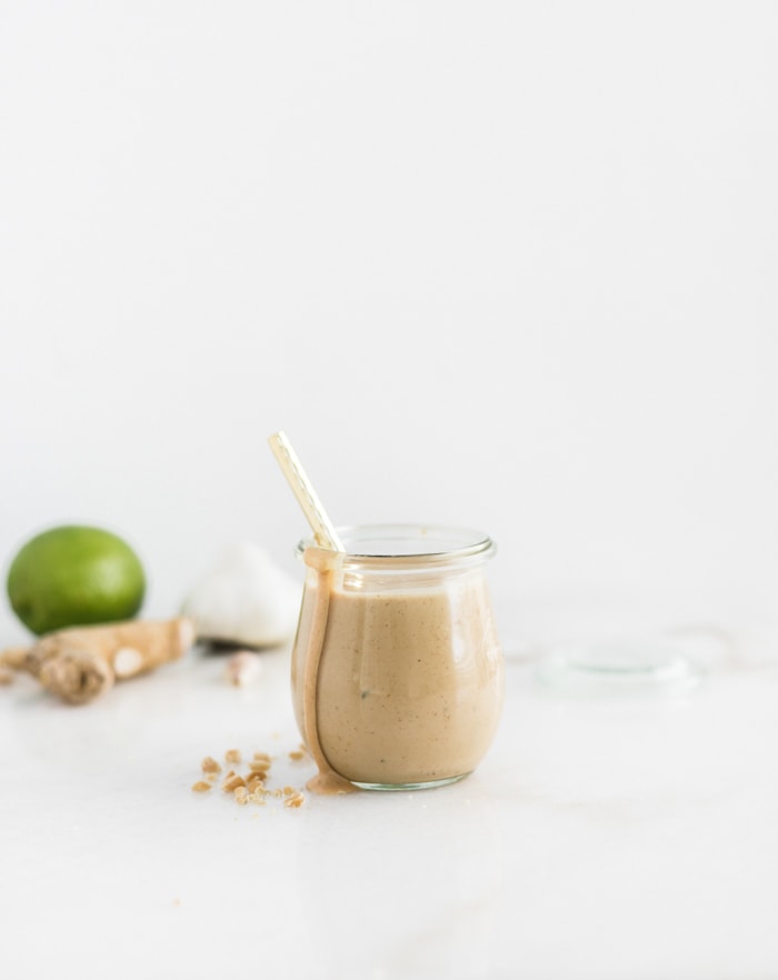 all purpose thai peanut sauce in a glass jar with a gold spoon in it.