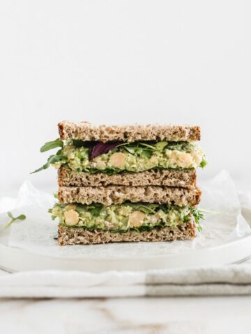 Close up of a smashed chickpea avocado salad sandwich cut in half stacked.